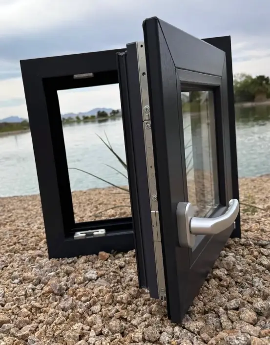 A black window frame sitting on top of gravel.