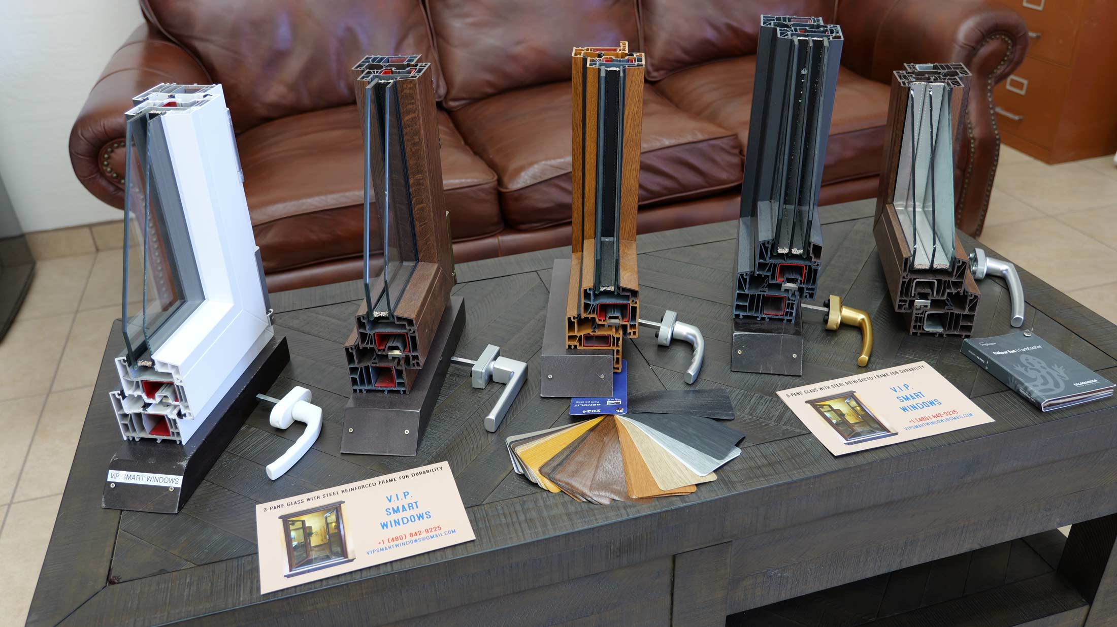 Cross-section models of VIP Smart Windows showcasing various window frame designs, materials, and finishes, displayed on a table with brochures and color samples, emphasizing premium window solutions for construction projects.