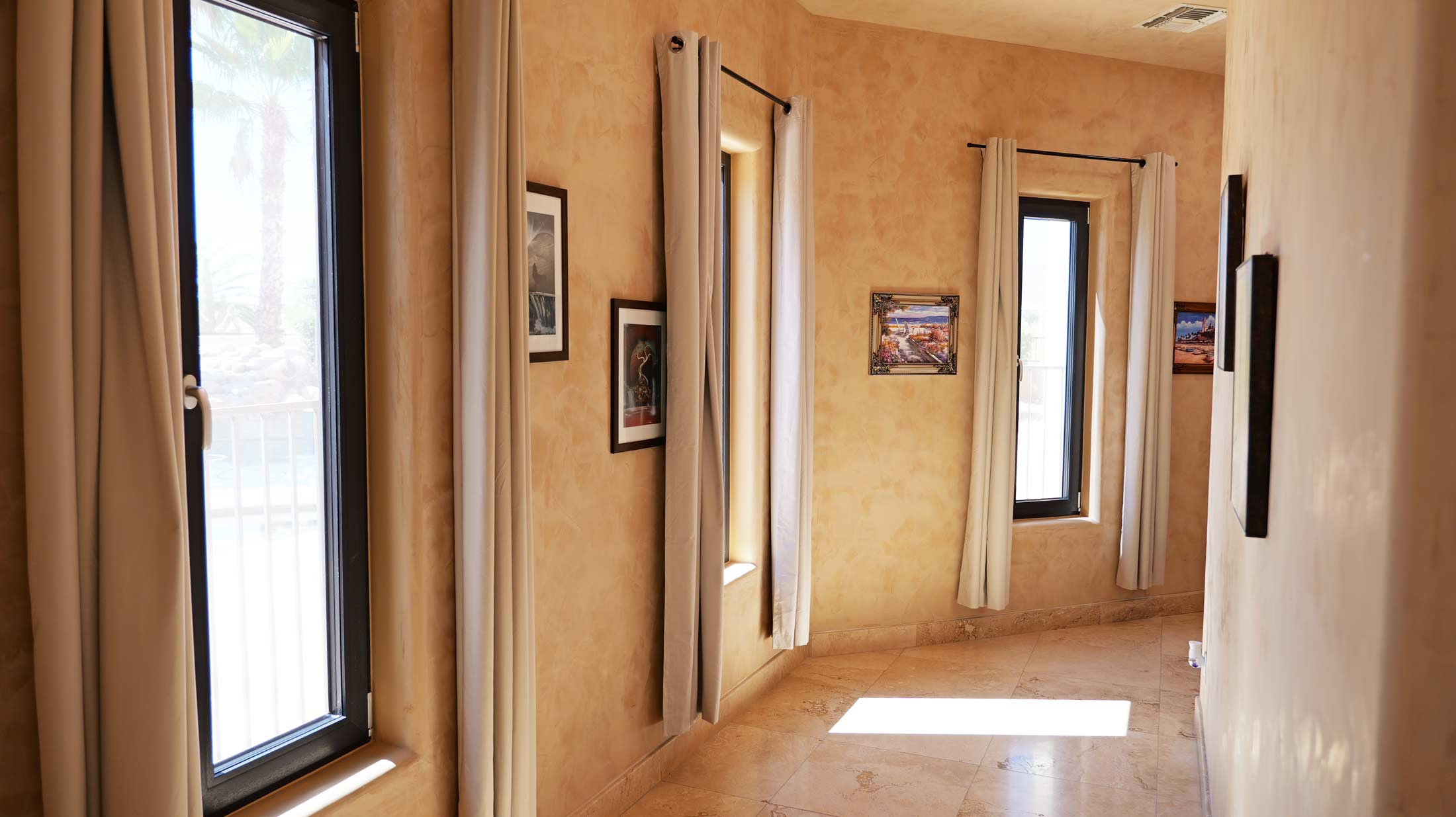 Interior hallway featuring VIP Smart Windows with black frames, beige curtains, and artwork on textured walls, emphasizing design and natural light.