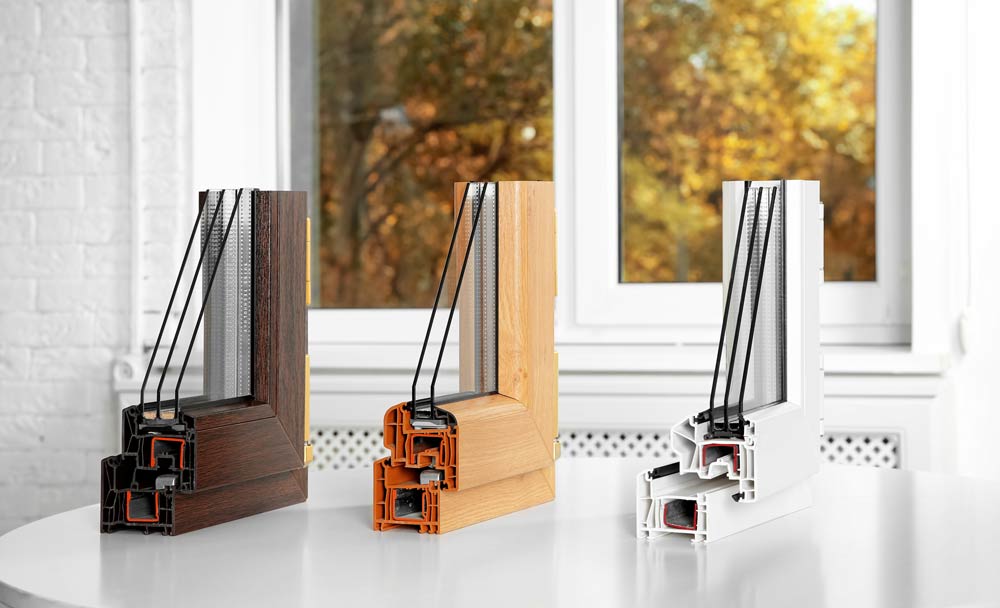 Energy-efficient window cross-section showcasing three styles: dark wood, light wood, and white, highlighting premium design and craftsmanship, with a backdrop of autumn foliage.
