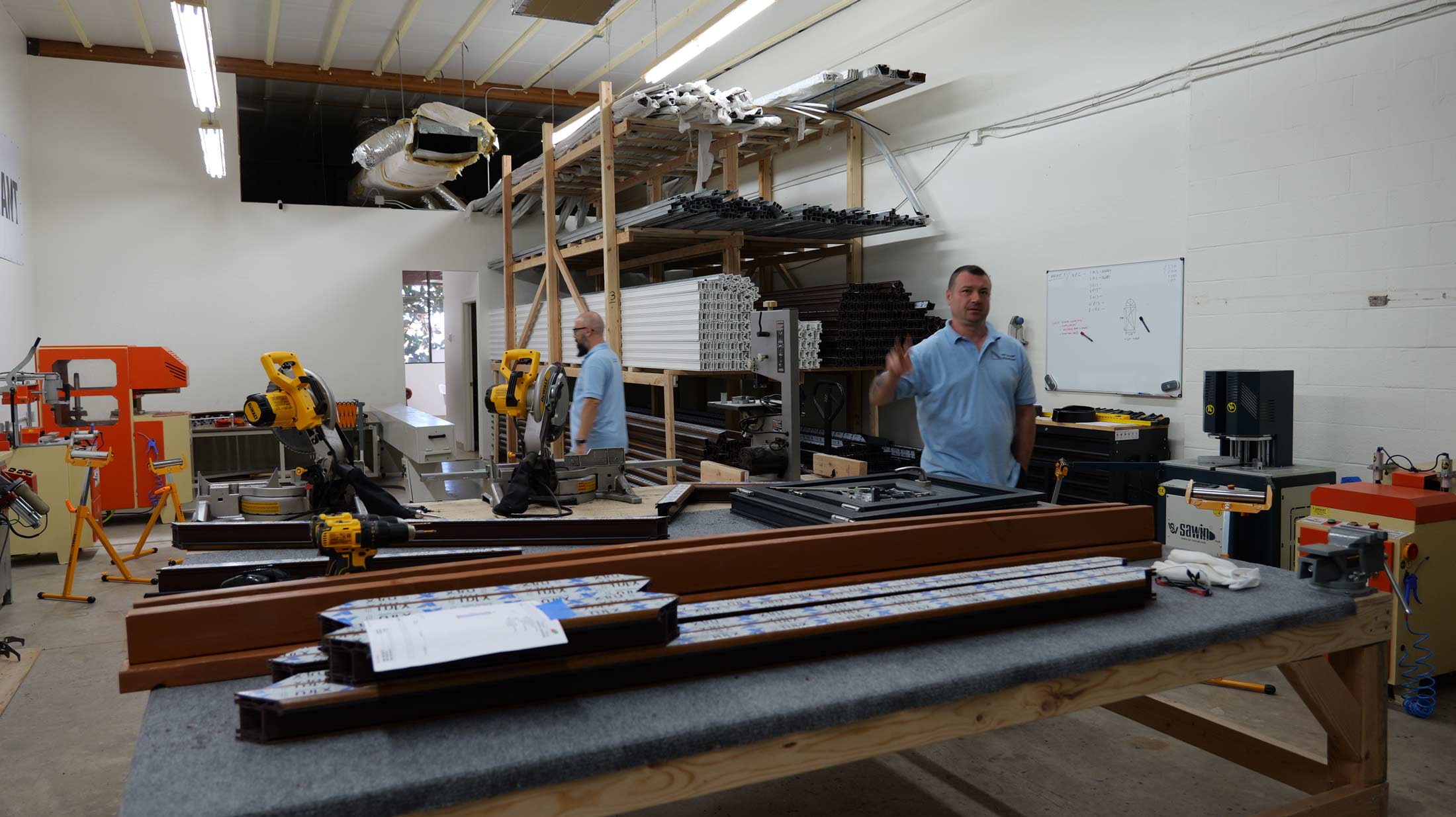 Manufacturing facility of VIP Smart Windows showcasing workers assembling high-performance window and door systems, with tools and materials prominently displayed.