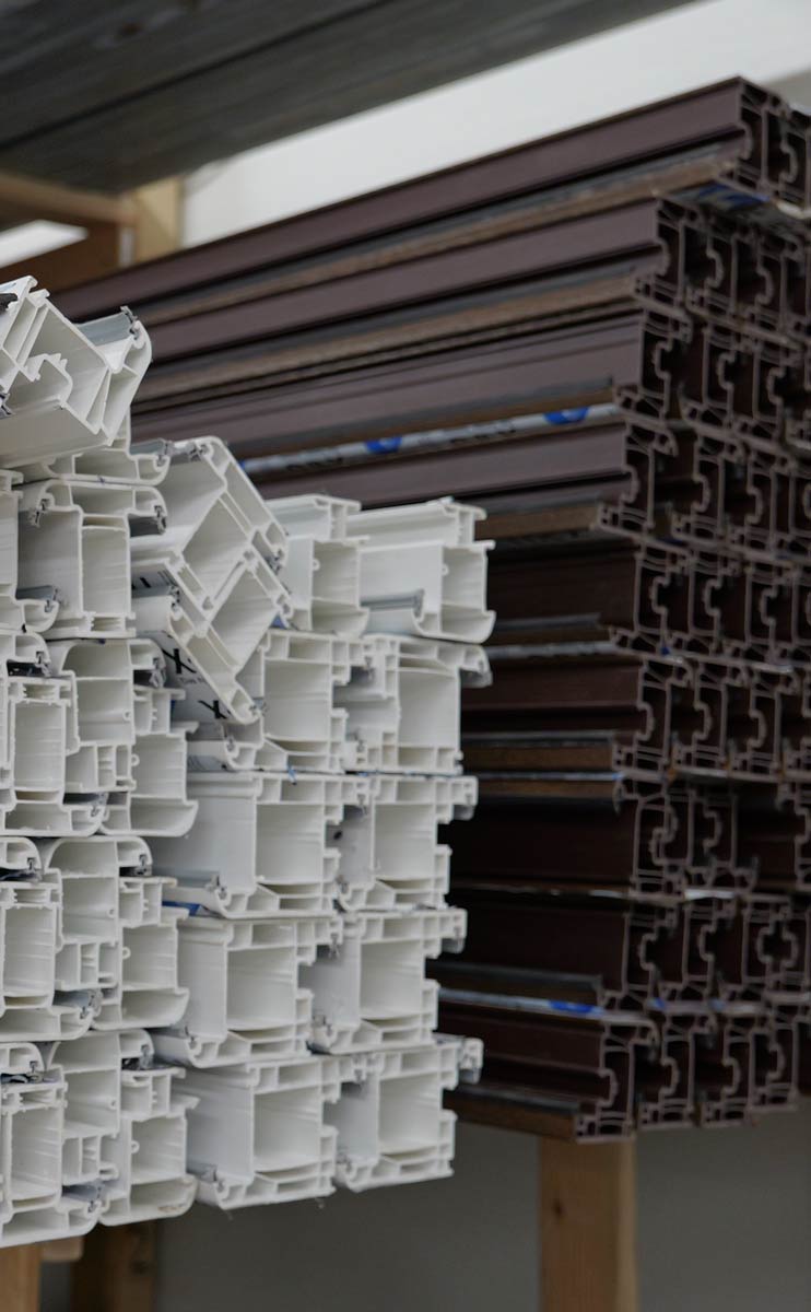 Stacked white and brown window frame profiles showcasing energy-efficient construction materials for modern residential builds, highlighting VIP Smart Windows' supply inventory.