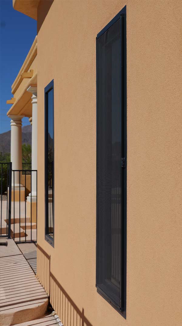New construction exterior of a home featuring VIP Smart Windows, showcasing sleek black window frames and a smooth stucco wall in a warm beige tone, with a glimpse of a railing and architectural details in the background.